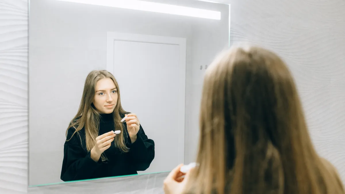 Người dùng chuẩn bị tháo lens an toàn trước gương sáng